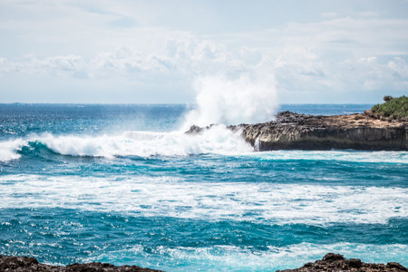 A beautiful blue wave crashes down at the rocks in Devil's Tear, tropical island Nusa Lembongan,...
