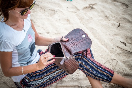 Fashion young woman on the beach. Luxury snakeskin python handbag in her hands. Sunny day. Tropical island Bali, Indonesia.の写真素材