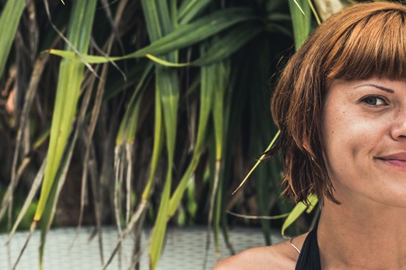 Close up of half face portrait of young beautiful woman on green leafs back. Tropical island Bali, Indonesia. Beautiful fashion spa scene.の写真素材