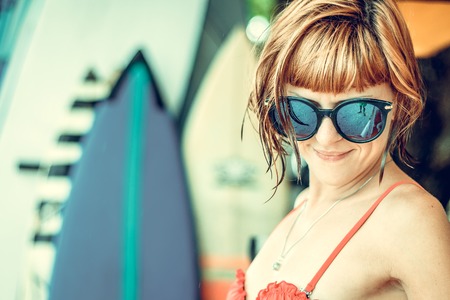 Young sexy girl in red swimsuit - surfer with surf board posing on the Nusa Dua beach, tropical Bali island, Indonesia. Family lifestyle, people water sport lessons and beach swimming activity on summer vacation.の写真素材