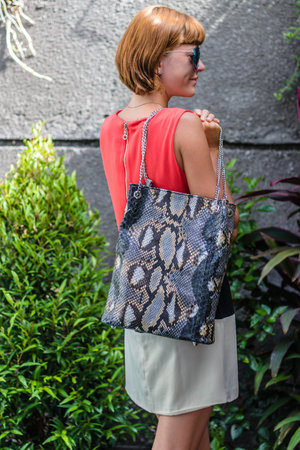 Fashionable young woman with stylish snakeskin python handbag, accessories, sunglasses, summer day,...