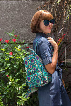 Elegant outfit. Close up of stylish snakeskin python backpack in woman s hand. Female fashion...