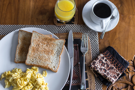 Toast with fried egg, on white plate in luxury tropical villa. Delicious breakfast with coffe and orange juice. On a light background, top view. Bali, Indonesia.の写真素材