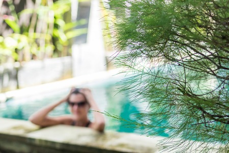 Young woman in swimsuit in swimming pool in gorgeous resort, luxury villa, tropical Bali island, Indonesia.の写真素材