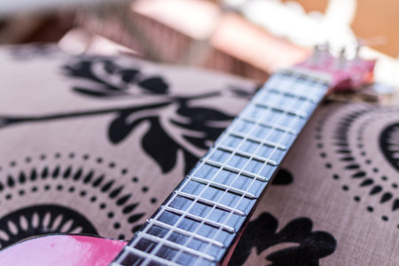 Small pink ukulele guitar on a tropical background. Music instrument.