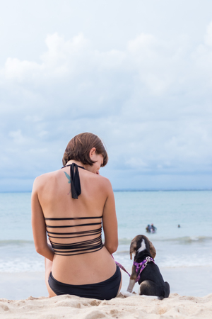 Young attractive girl with her pet dog Beagle at the beach of tropical island Bali, Indonesia. Happy moments.の写真素材