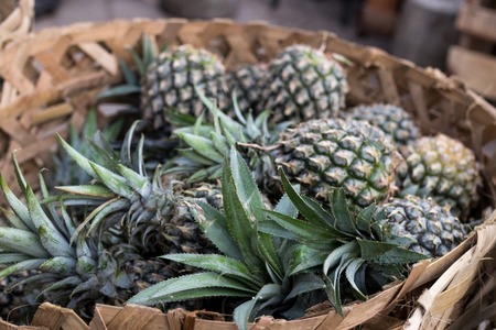 Pile of tropical pineapples fruits in basket for sell in tradtional farmer market of Bali island.の写真素材