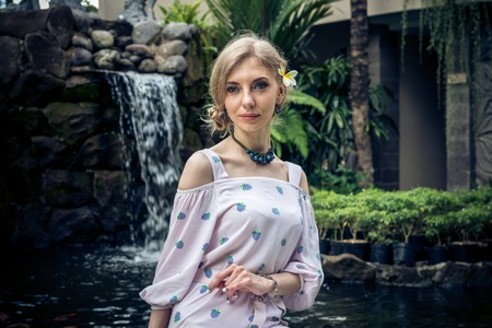 Woman is posing in a tropical garden of Bali island, Indonesia. Garden waterfall on a background. Sexy young woman.の写真素材