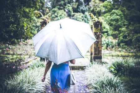 Woman with umbrella in the tropical park of Bali island, Indonesia.の写真素材