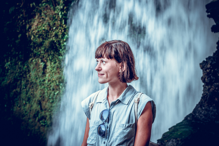Woman on a waterfall deep in the tropical rain forest of Ubud, tropical Bali island, Indonesia. Exotic scene of tropics. Freedom concept.の写真素材