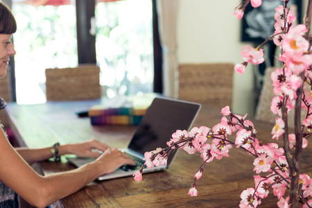 Attractive female university student using laptop on a wooden table.の写真素材
