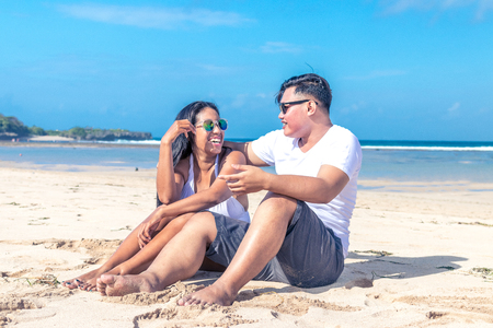 Asian couple sitting on the beach of tropical Bali island, Indonesia.の写真素材
