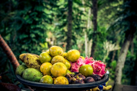 Mixed tropical fruits in the basket on a rainforest background. Bali island.の写真素材