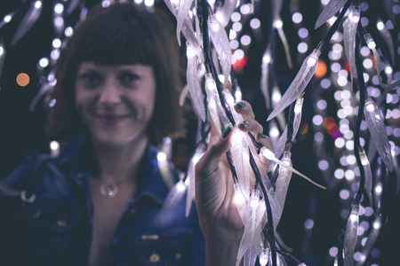 Closely image of young woman among christmas garlands lights. Bali light festival, Indonesia.の写真素材