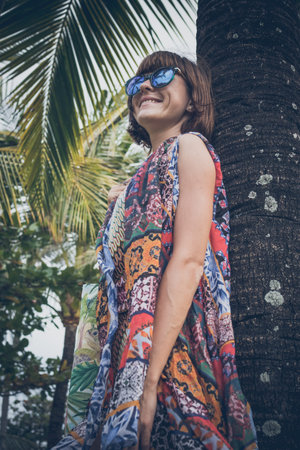 Tropical woman vacation concept. Young woman and palm. Bali island, Indonesia.