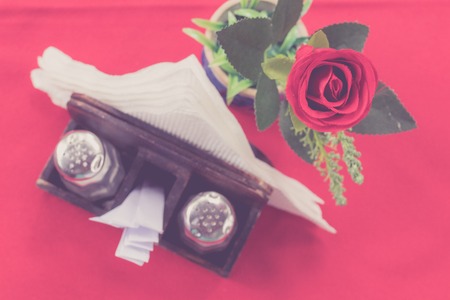Closeup of beautiful fresh rose on a red table background. Restaurant. Bali island.の写真素材