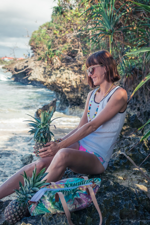 Tropical summer woman with pineapple. Outdoors, ocean, nature. Bali island paradise. Indonesia.の写真素材