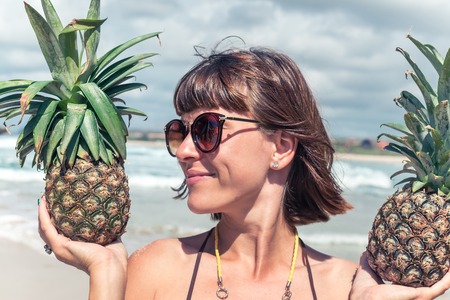 Tropical summer woman with two pineapples in her hands. Outdoors, ocean, paradise, Bali.の写真素材