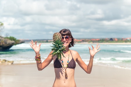 Tropical summer woman with pineapple on her head. Outdoors, ocean, nature. Bali island paradise.の写真素材
