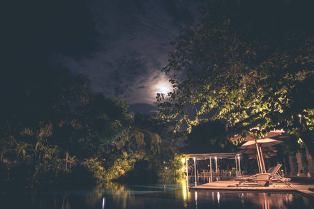 Swimming pool in luxury modern resort with tropical garden at night time.の写真素材