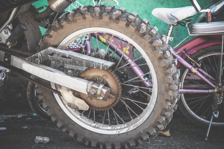 Closeup view of a rear wheel and drive wheel hub of a dirty, grunge motocross motorcycle, which lays on the ground.の写真素材