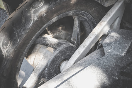 Closeup view of a rear wheel and drive wheel hub of a dirty, grunge motocross motorcycle, which lays...
