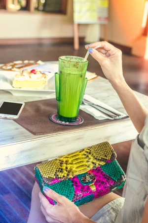 Fashion luxury snakeskin python handbag on the wooden table in restaurant. Bali island.の写真素材