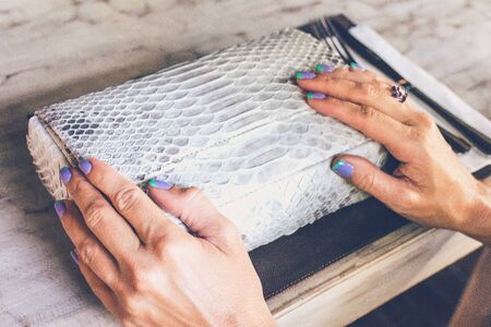 Fashion luxury snakeskin python handbag on the wooden table in restaurant.の写真素材
