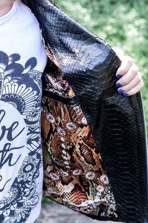 Sexy young woman in luxury snakeskin python black jacket posing outdoors in the park. Bali island, Asia.の写真素材