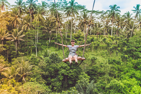 Young tourist woman swinging on the cliff in the jungle rainforest of a tropical Bali island.の写真素材