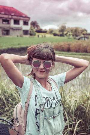 Outdoor fashion portrait of young beautiful lady in sunglasses, summer concept. Rice field on a background. Tropical island of Bali, Indonesia.の写真素材