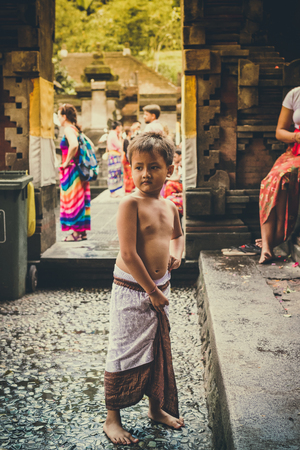 BALI, INDONESIA - DECEMBER 5, 2017: Closeup portrait of cute asian balinese boy outdoors in the temple. Ubud area, Bali island, smiling girl.のeditorial素材