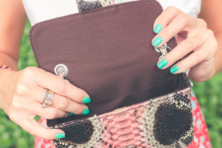 Woman hands with luxury handmade snakeskin leather handbag. Python snake fashionable handbag. Outdoors, Bali island.の写真素材