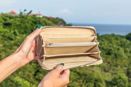 Woman hand holding luxury snakeskin python wallet on a tropical green background.