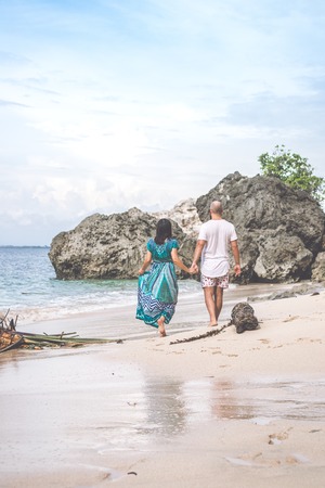 BALI, INDONESIA - JANUARY 10, 2018: Happy young honeymoon couple walking on the beach. Ocean, tropical vacation on Bali island, Indonesia.のeditorial素材