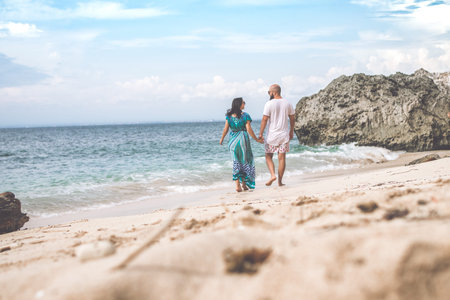 BALI, INDONESIA - JANUARY 10, 2018: Happy young honeymoon couple walking on the beach. Ocean,...