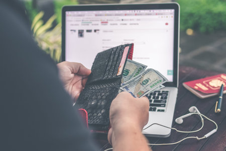 Man doing online shopping with credit card, laptop and luxury snakeskin python wallet. Man online...