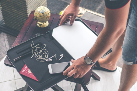 Man with luxury snakeskin python laptop case on a table outside the asian garden. Men fashion concept. Laptop bag.の写真素材
