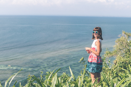 Young woman alone on the cliff with beautiful ocean background. Bali island.の写真素材