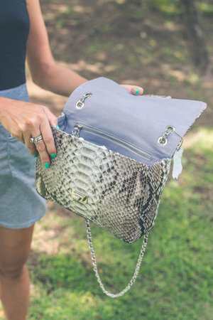 Woman hand with luxury snakeskin handbag outdoors. Tropical fashion exotic concept.の写真素材