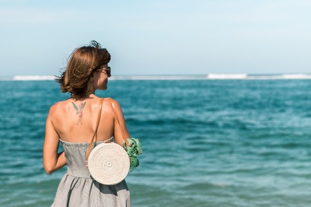 Woman with fashionable stylish white rattan bag and silk scarf outside. Tropical island of Bali, Indonesia. Rattan handbag and silk scarf.の写真素材