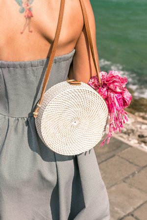 Woman with fashionable stylish white rattan bag and silk scarf outside. Tropical island of Bali, Indonesia. Rattan handbag and silk scarf.の写真素材