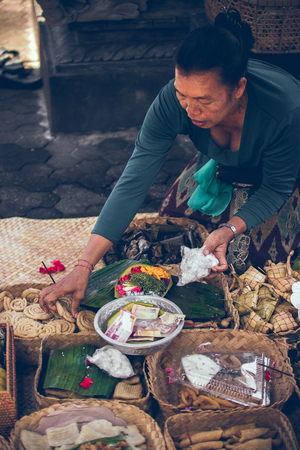 BALI, INDONESIA - APRIL 13, 2018: Woman with balinese offerings to Gods.のeditorial素材
