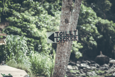 A horizontal view of classic simple design handmade wooden sign of toilet give direction to WC. Bali.の写真素材