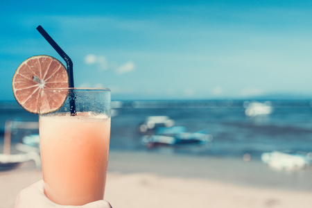 A glass of fresh and cold orange juice against the background of the sea. Bali island.の写真素材