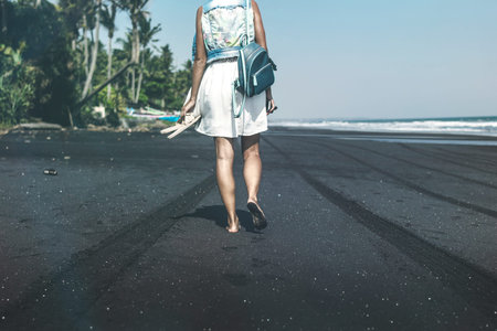 Young woman on a black sand beach, Bali island.