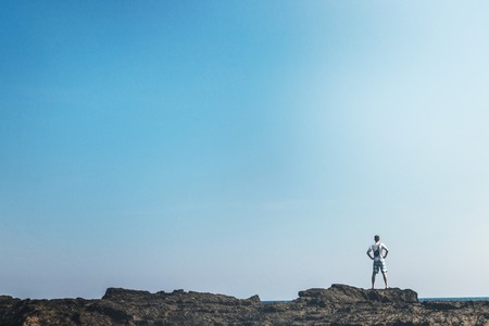 Man standing on the rocks in the ocean of Bali island. Indonesia.の写真素材
