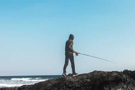 Fishermen standing on the rocks in the ocean. Bali island.の写真素材