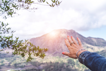 Woman hand on mountain background. Volcano Batur. Bali island.の写真素材