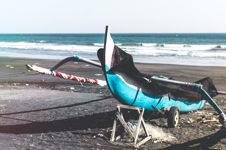 Old boat on the beach with black sand. Bali island.の写真素材
